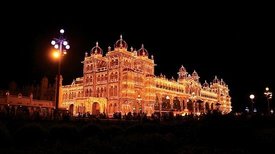 A far out view of the Mysore Palace in the night with lights on on the exterior.