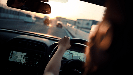 A woman driving a car with her hands on the steering
