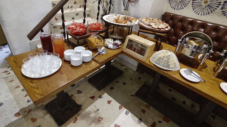 A buffet spread for breakfast featuring fruits, baked good, juice and cutlery on multiple tables | Kings International Juhu