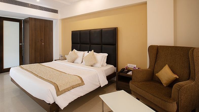 a double bed with a single seater sofa on the side inside one of the rooms - VITS Shalimar, Ankleshwar