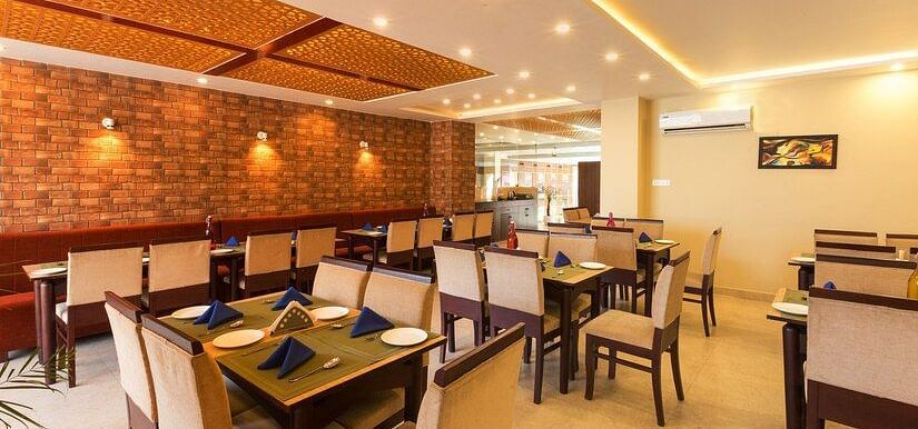 image of the indoor dining area with dining tables surrounded by off white cushioned chairs - ZENQ SIGNATURE INN, MCLEODGANJ