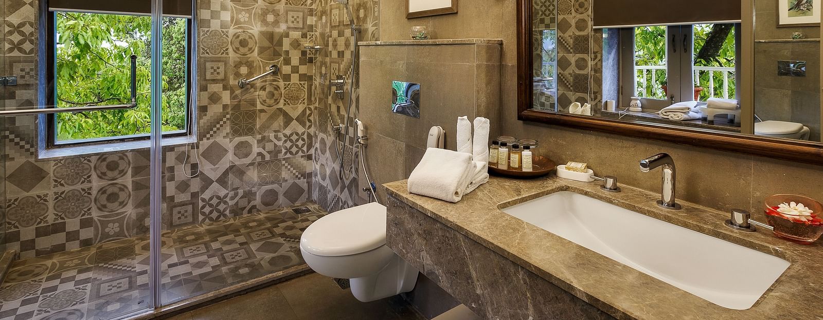 An image featuring a washroom, a big wooden mirror, marble floor and the glass separator for bath area - The Naini Retreat, Nainital.