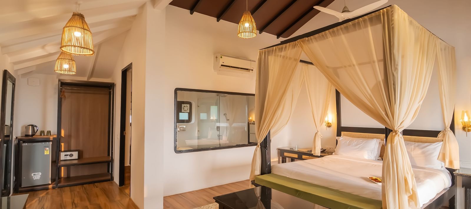 A crafted bedroom with a bedding having cosy mattress, curtains and fancy lightings, with a see through washroom - Crescent Resorts