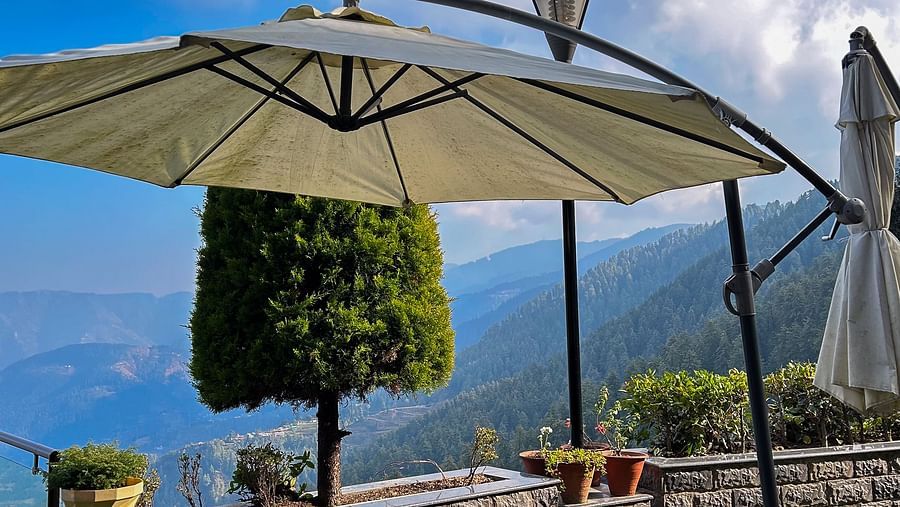 Outdoor dining setup under a parasol with majestic mountain views at Aranya Himalayan Retreat, Mashobra
