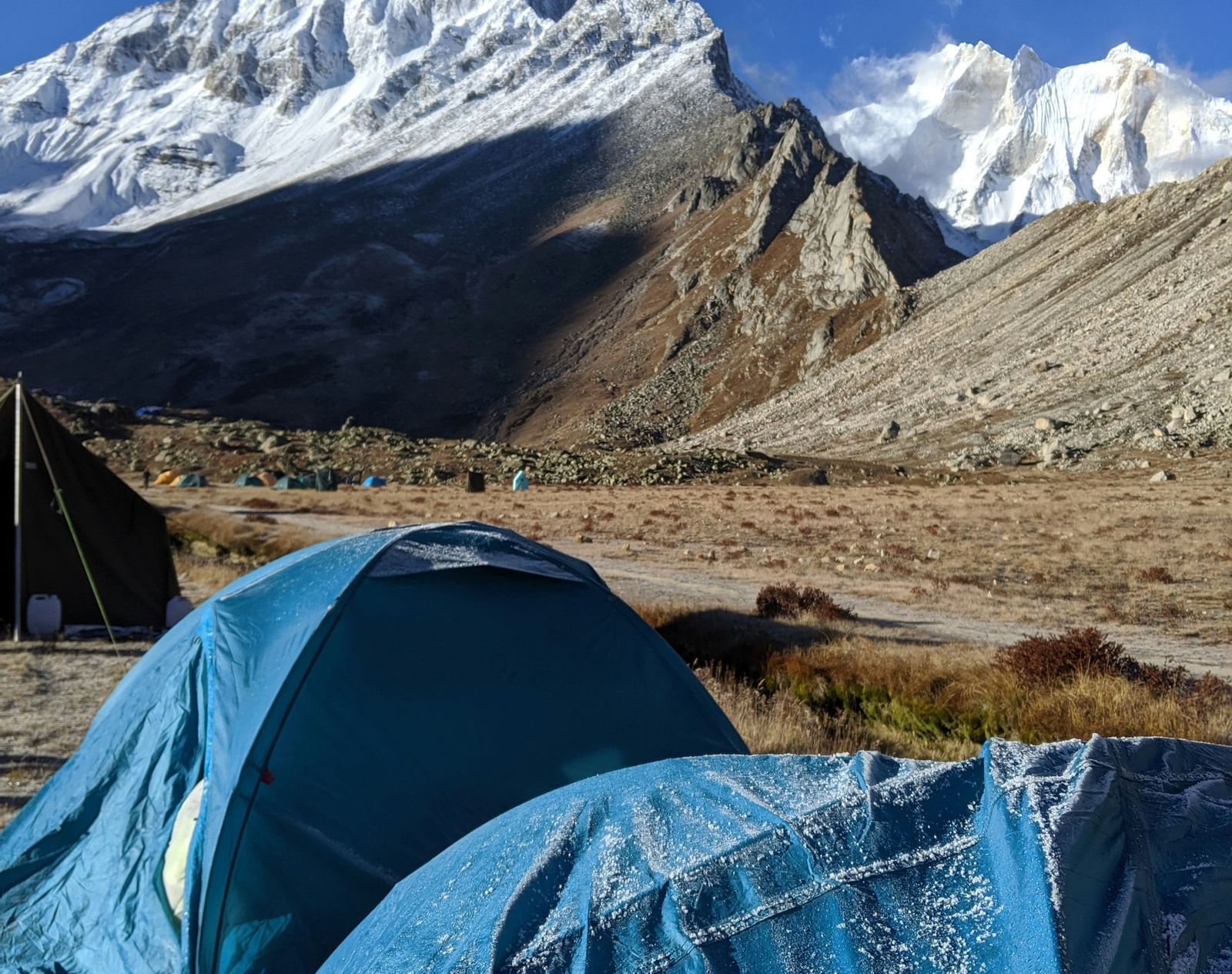 image of snow capped mountains with tents arranged in front of it.