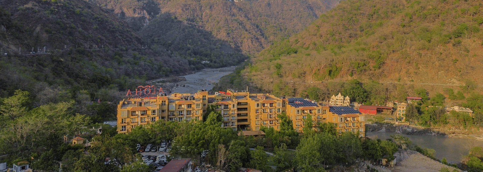 A scenic view of Perfectstayz Value Alpine Retreat, Rishikesh nestled among lush green hills.