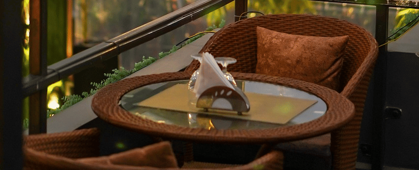 Two chairs facing each other on a terrace with warm lights besides it on a late evening.