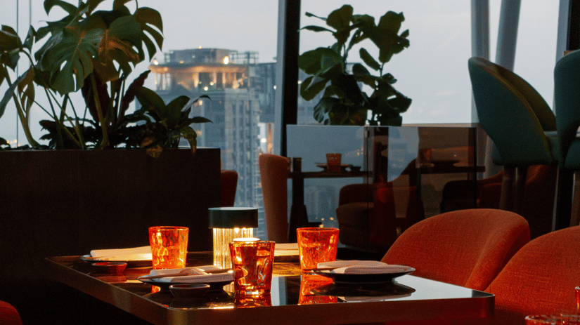 Elegant dining lounge with warm lighting, modern seating, and city views through large windows