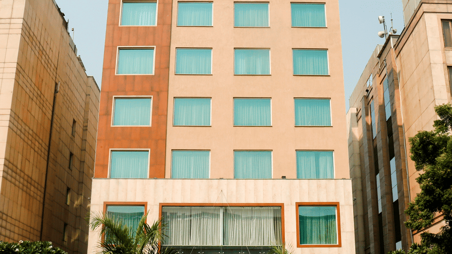 Facade of the Nemesia City Center in Gurugram featuring the hotel's entrance and its surrounding greenery.