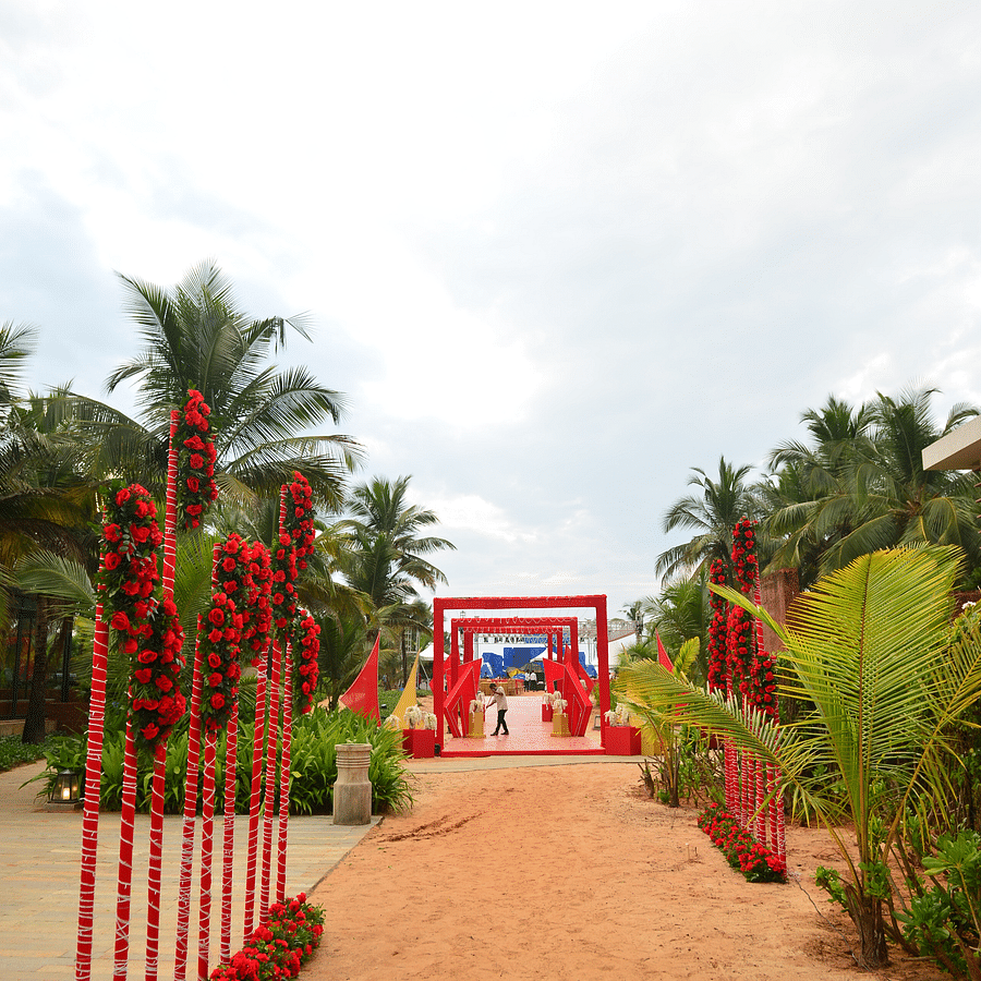 Red flower arrangements by a sandy pathway at one of the best wedding venues in south goa