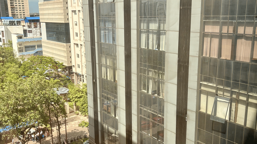 Portrait shot taken from Senses Hotel showing a glass framed building, a busy road and dark cloudy sky.