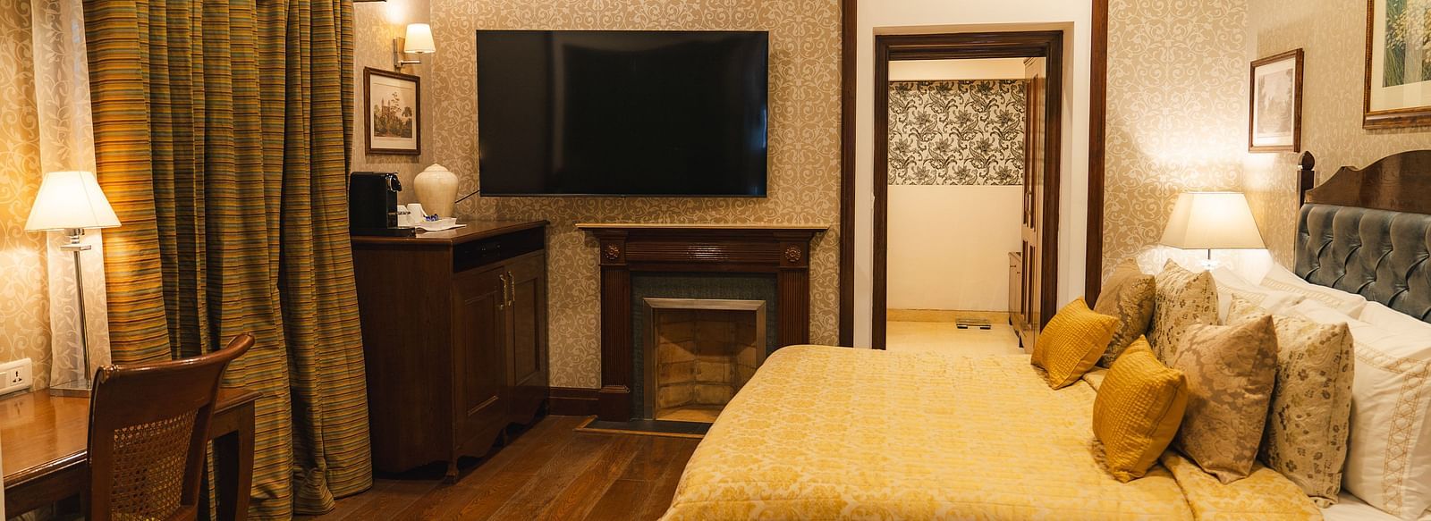  A cosy room featuring a comfortable bed, wall-mounted television, and classic wooden furniture.