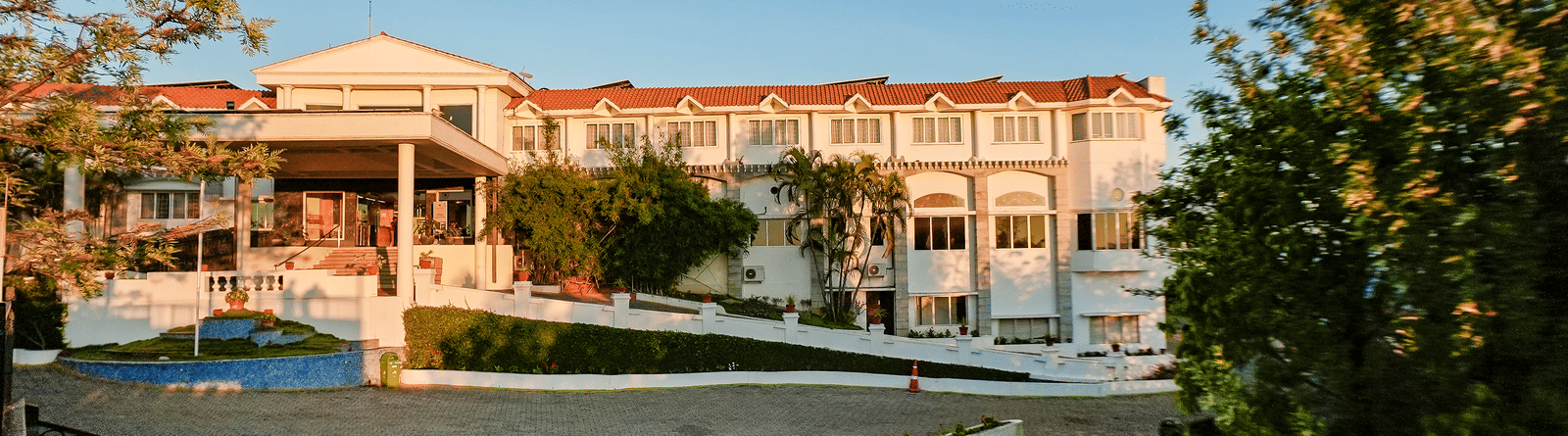 Grand Palace, Yercaud with view of  main building, walkway, fence and green garden surrounding the hotel.