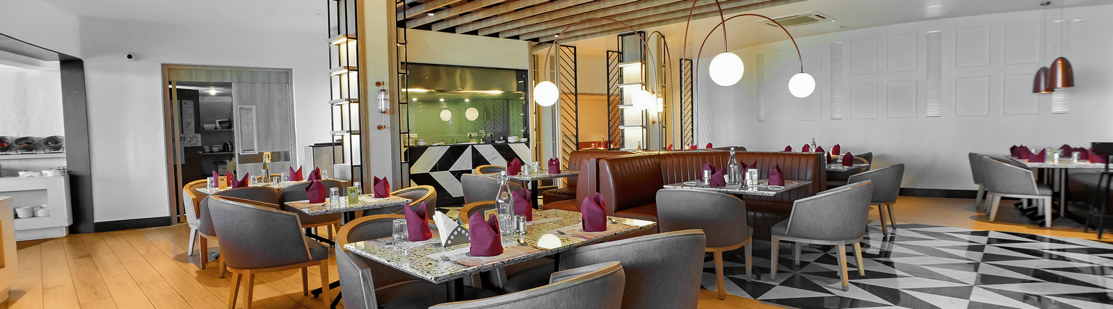 Orange Restaurant at Grand Palace, Yercaud showing dining setup with tables, chairs, buffet counter, and wooden flooring.