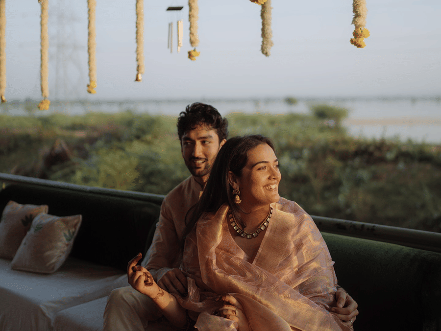 Couple sitting together on a bench beneath decorative hanging flower strings at Umaid Palace.