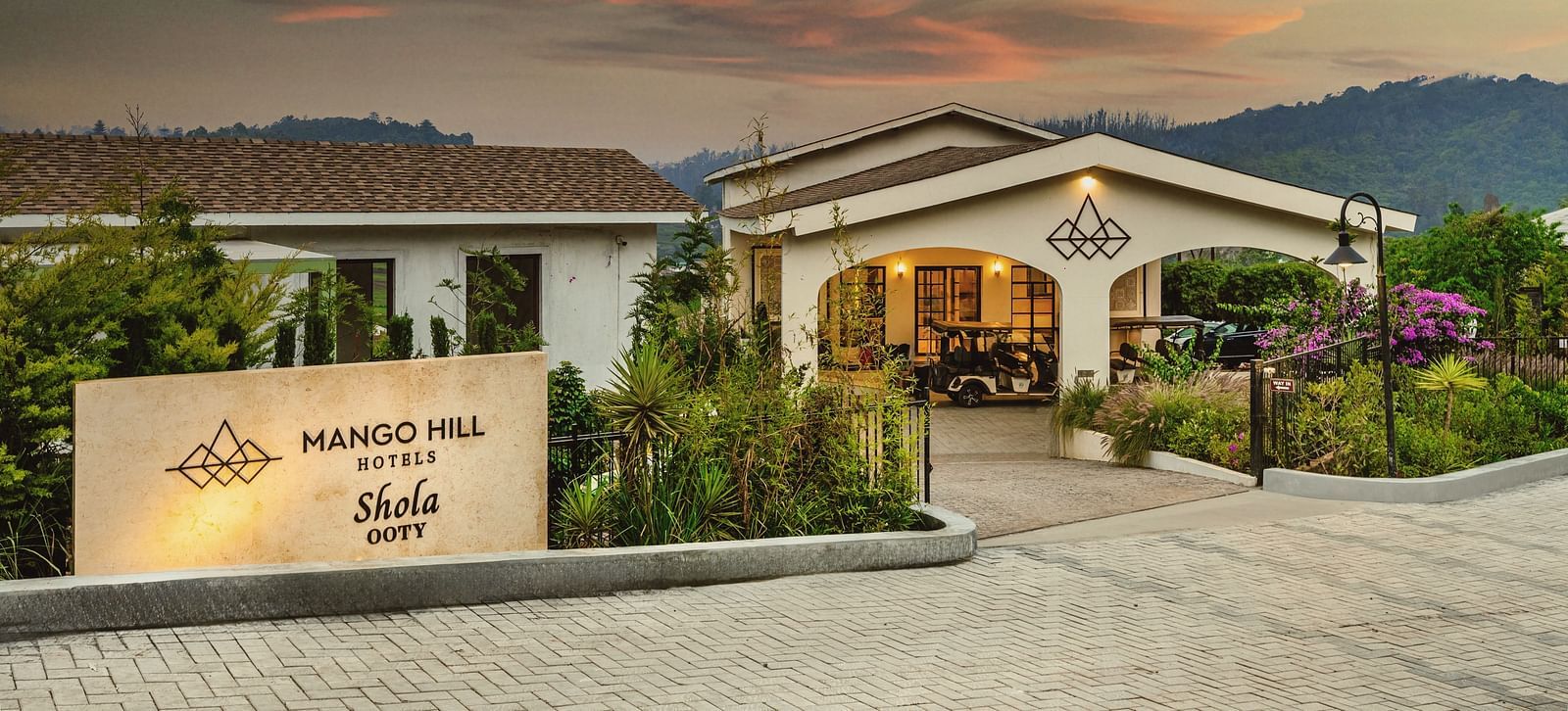 Panoramic view of Mango Hill Shola, Ooty, nestled within tea plantations and hills, blending into the expansive surrounding landscape.