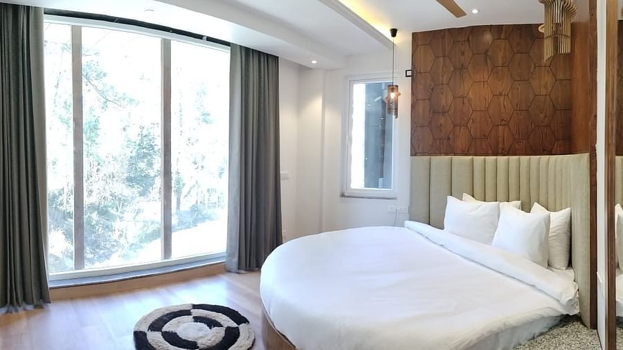 A large bed next to a large window in Deluxe Non-view Room at DLS Ark Holiday Inn, Banikhet.