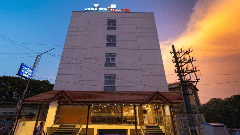 The facade of VITS Select, Bengaluru, as seen from the front, featuring stairs leading up to the hotel with a vibrant sky in the background.