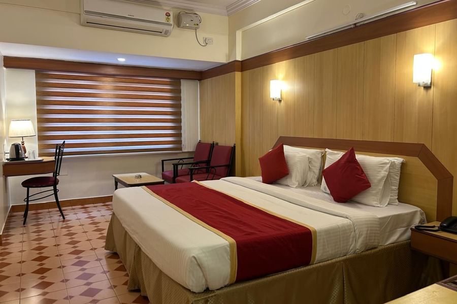 Spacious guest room at Hotel Swagath, Bangalore with two twin beds, cushioned headboards, and warm lighting.
