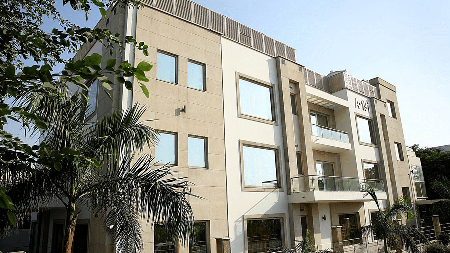 A modern beige multi-storey building stands under a blue sky at Eastlynn Collections Huda City Centre, Gurugram.