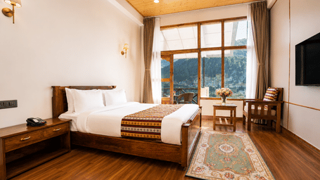 Premium Room with Balcony at Summit Rungkhung Village Resort - The Signature Collection consists of a bed with pillows, side tables, a wall-mounted television, a floor rug, and glass doors opening to an outdoor area.