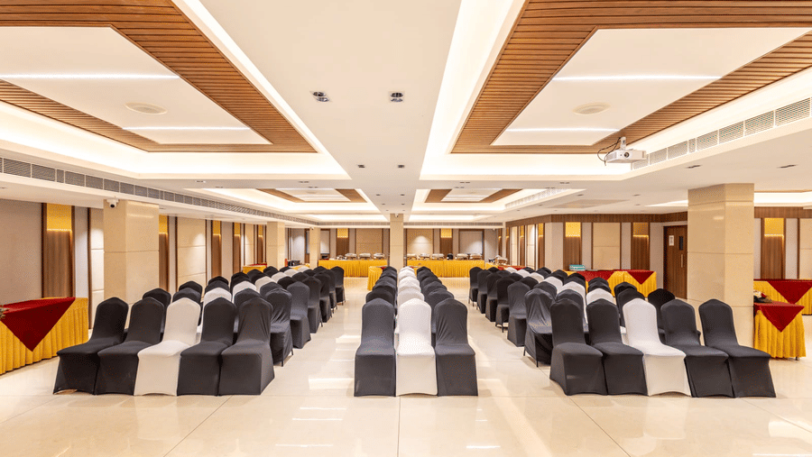 Spacious interior of S Convention Centre at S Hotels, Chennai, with theatre seating, modern recessed ceiling panels, and a buffet setup in the background.