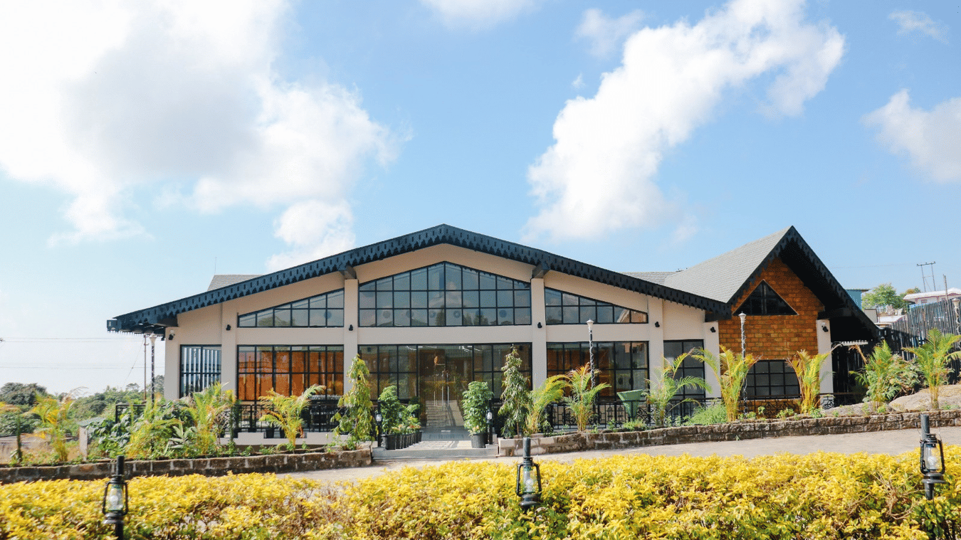 The Mausmai Ballroom features a grid-patterned glass facade, flooding the space with natural light and offering panoramic views of the lush garden outside.