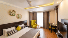 Super Deluxe Room at Rockland Hotel, CR Park, featuring a cozy bed and a chair in the corner.