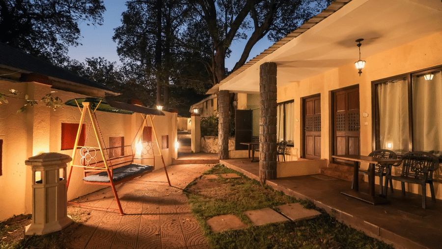 Dusk view of Adamo The Village courtyard showing a paved area with a small swing set and covered patios of adjacent buildings.