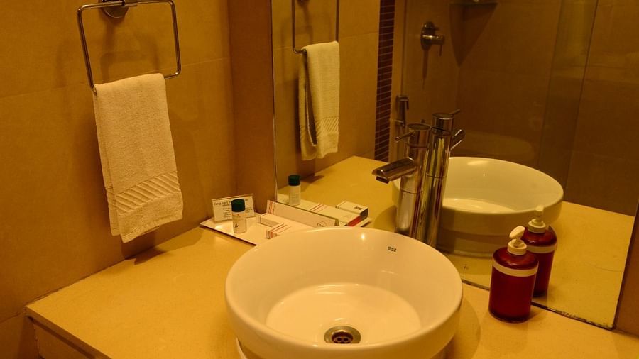 Modern hotel bathroom sink area with round ceramic basin, chrome faucet, mirror, hand towel, toiletries, and soap dispensers - Citrus Classic, Outer Ring Road, Bangalore