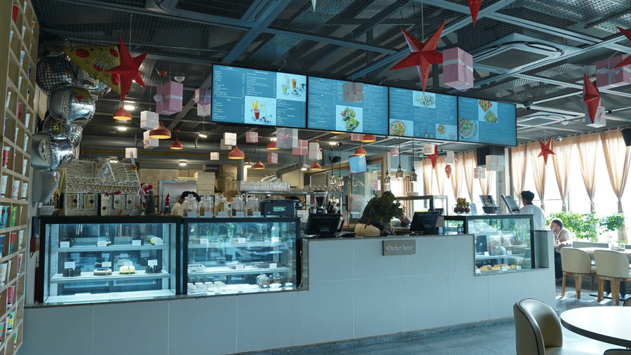 A food counter of Falaknuma restaurant with glass display units, menu boards mounted above, preparation stations, and service staff standing behind the counter at Clarks Avadh, Lucknow.