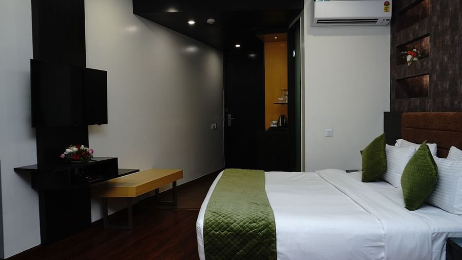 An image of a Deluxe Room at Five Elements Hotels North Avenue, Delhi featuring a double size bed, a flat TV screen, AC, tea and coffee maker, and other elements