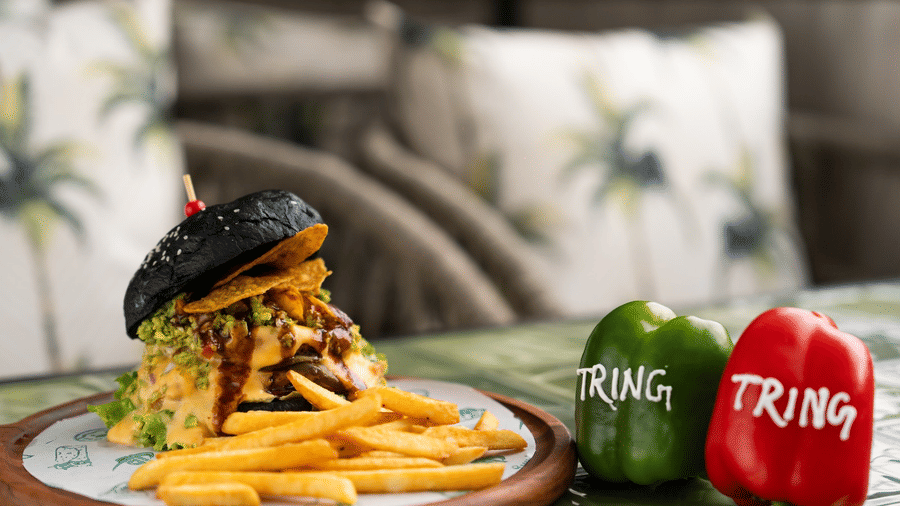 An image of a wooden plate with a burger, French fries, and two capsicums, each labelled Tring.