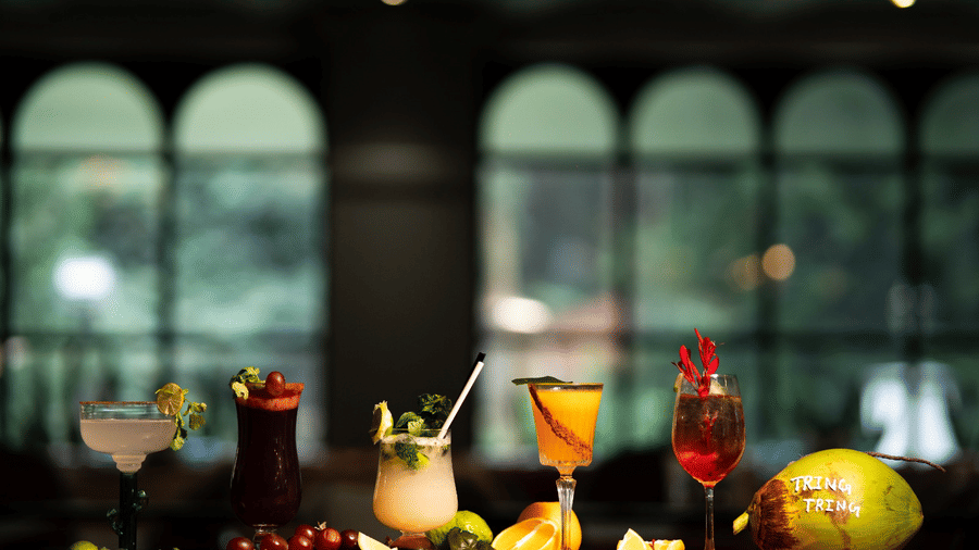 An image showcasing a variety of mocktails, cocktails, and fresh fruits arranged on a wooden counter.