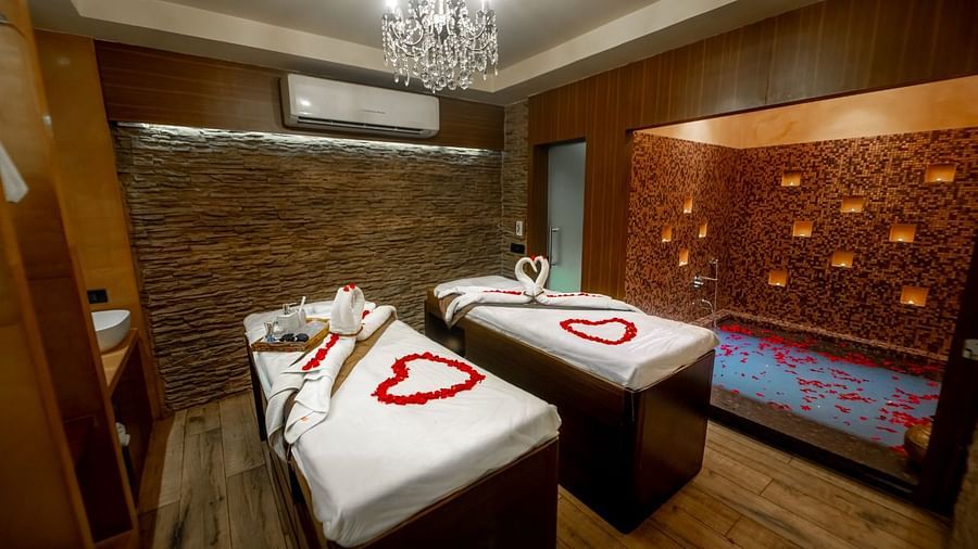 a couple massage table with a chandelier hung on the roof inside the massage room - IOSIS Spa & Wellness
