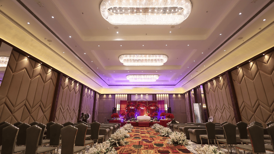Pride Premier Alwar | a banquet hall with several chairs, decorated walls and chandeliers.
