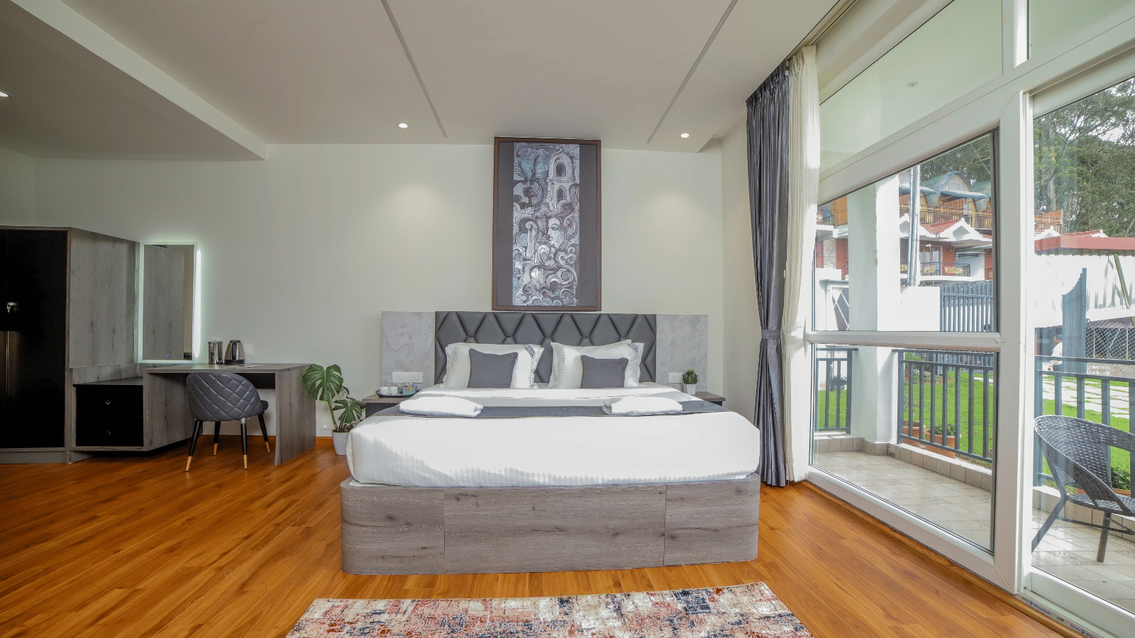 Direct view of the queen size bed beside large glass windows and a balcony at MYST Resorts, Doddabetta, Ooty.