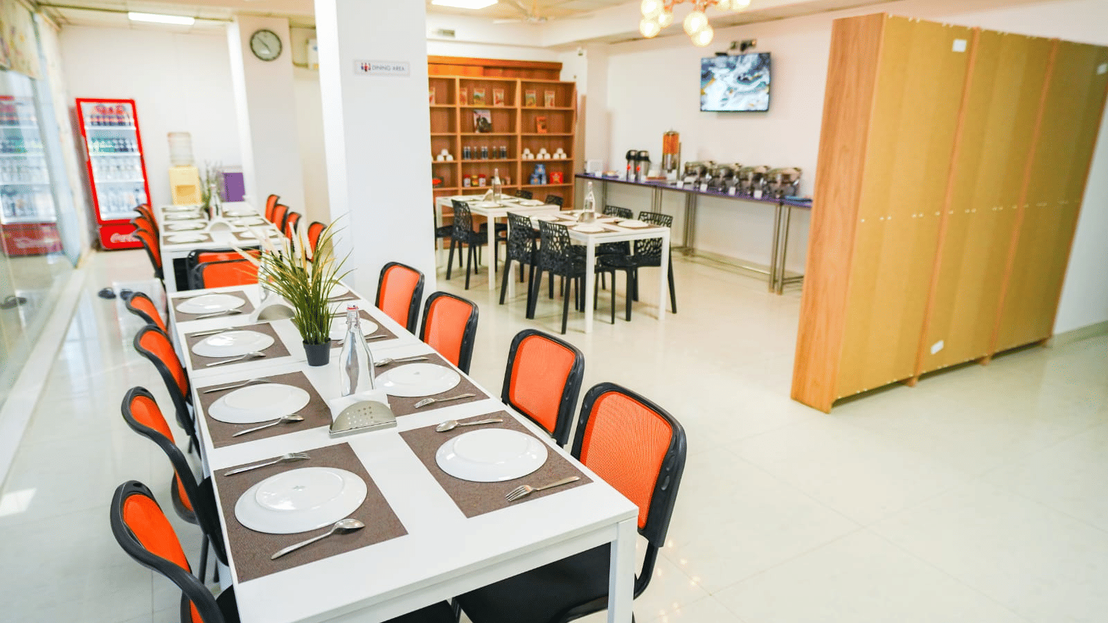 An indoor dining area featuring a long table with placemats and chairs neatly arranged around it, and a serving counter to the side at Sunrise A Boutique Hotel, Hyderabad.