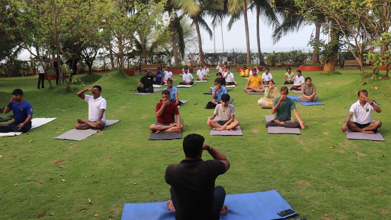 People practising yoga in the garden area at Swosti Resorts on a sunny day