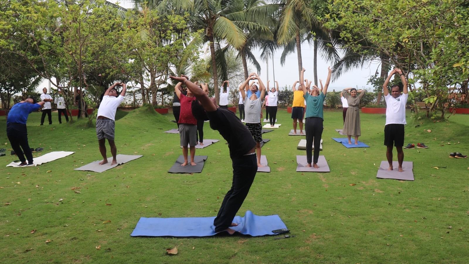 People practising yoga in the garden area at Swosti Resorts on a sunny day