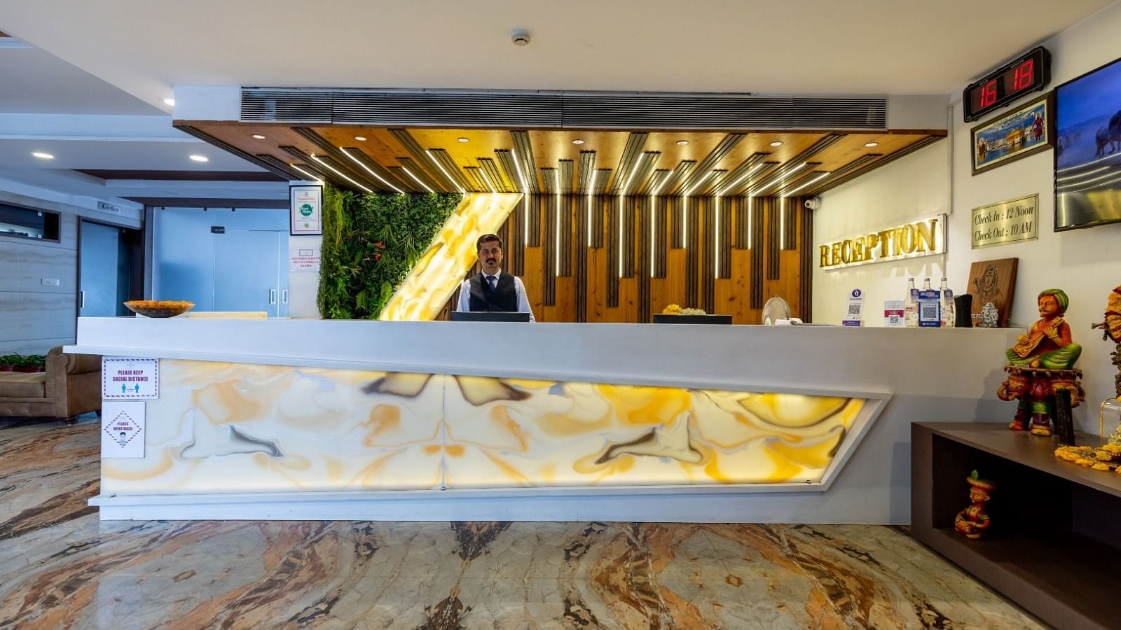A modern hotel reception desk with warm lighting and cultural decor - TGI Insignia, Bhopal
