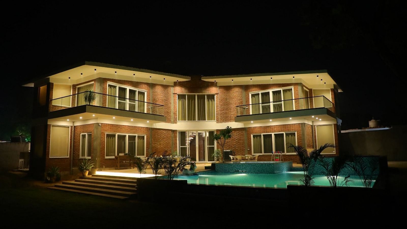 Tisya farms illuminated by warm glowing lights under the night sky.