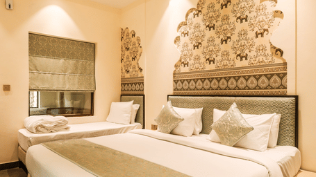 A bedroom with double bed, headboard design, and side tables at Beelwa Palace, Jaipur