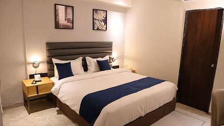 A stylish bedroom at Lords Eco inn Jamnagar Maheshwari Nagar with a large bed two bedside tables and artwork.