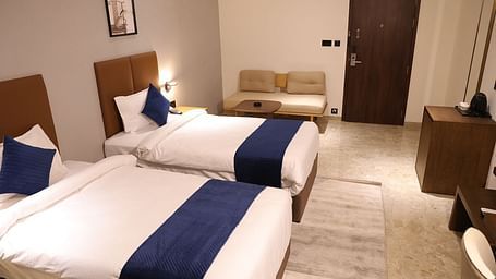 A twin bed room at Lords Eco inn Jamnagar Maheshwari Nagar offering comfortable accommodation and modern design.