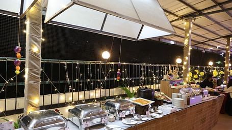 An outdoor dining area at night featuring a buffet station under illuminated canopies at Lords Inn Vadodara.
