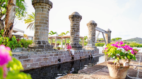 A monument surrounded by potted flower plants near Tamarind Hills Resort and Villas, Antigua, and a couple of people relaxing