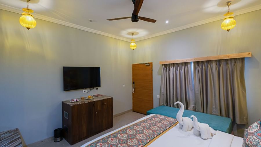 Guest room at Bamboo Saa Resort & Spa, Udaipur with TV, seating area and patterned bed runner.