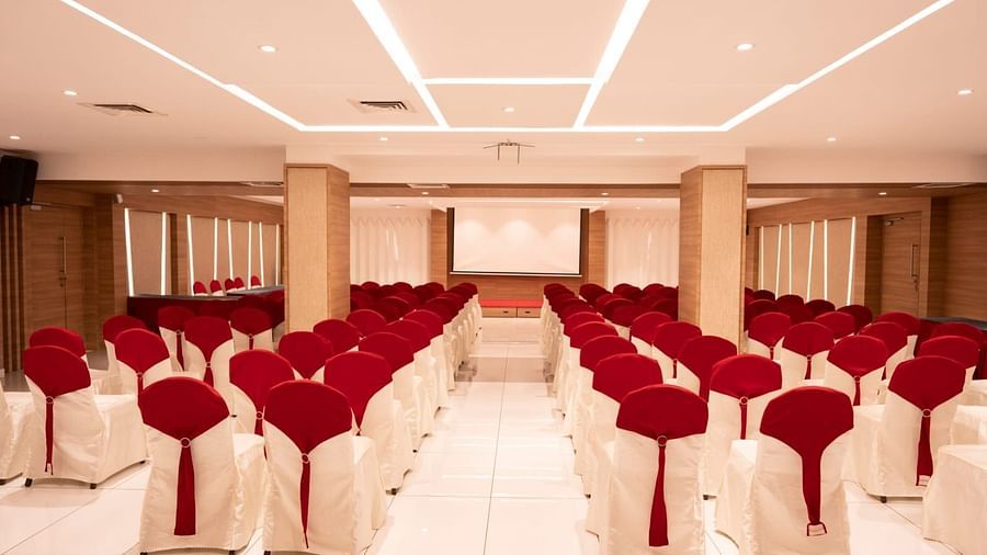 An event hall with white chairs facing the stage at Grand Ashok, Thanjavur.