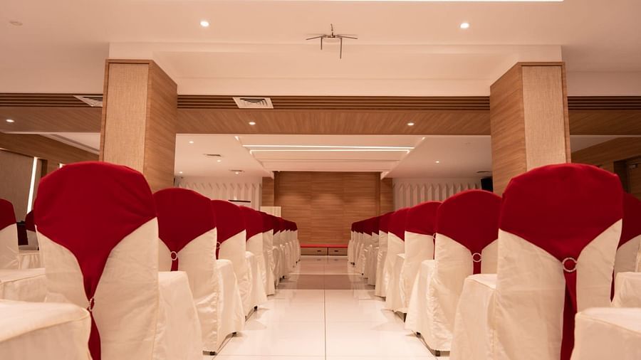 An event hall with white chairs facing the stage at Grand Ashok, Thanjavur.